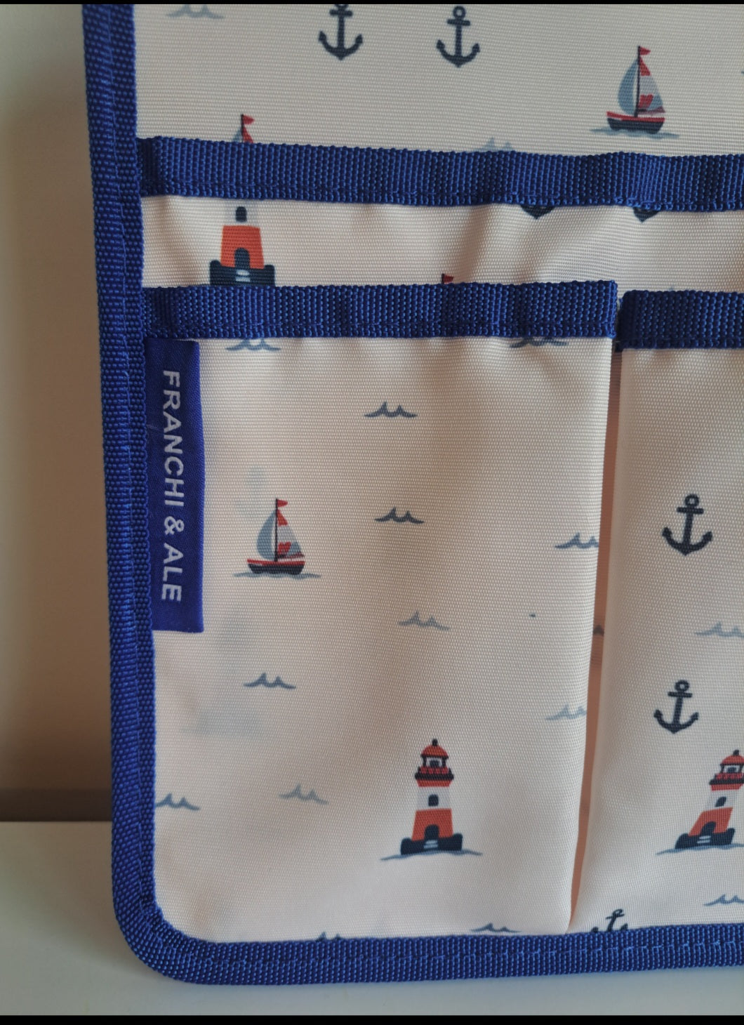 Franchi & Ale Bunk Bed Caddy front view showing nautical lighthouse and sailboat print with royal blue webbing and two front pockets